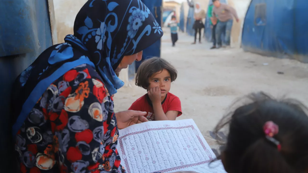 Woman sitting down reading to two chilren